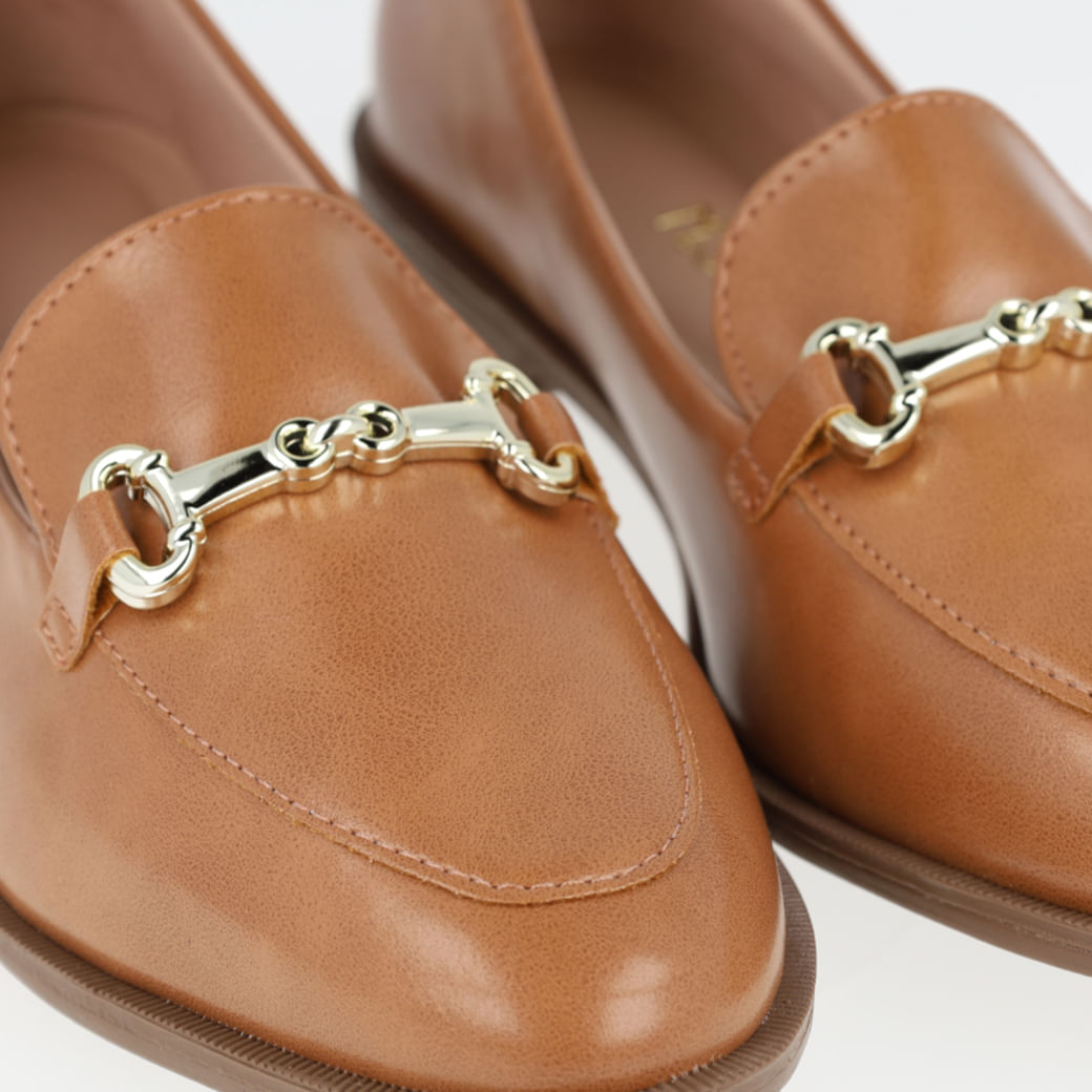 Par de sapatos mocassim feminino Napa capuccino com fivelas douradas sobre superfície branca